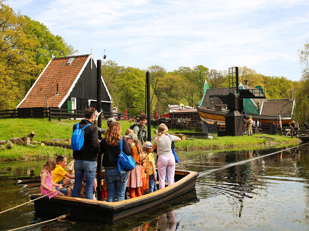 Dutch
                open air museum with people in a boat wacthing the buildings. When hovered over, it changes
                to reveal two Dutch windmill's on the park